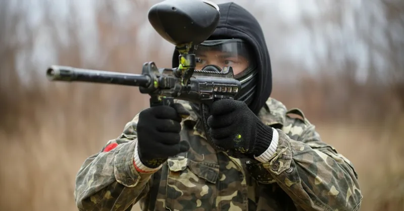 Joueur en tenue de camouflage en position de tir sur le terrain forestier de Tag Brussels en hiver